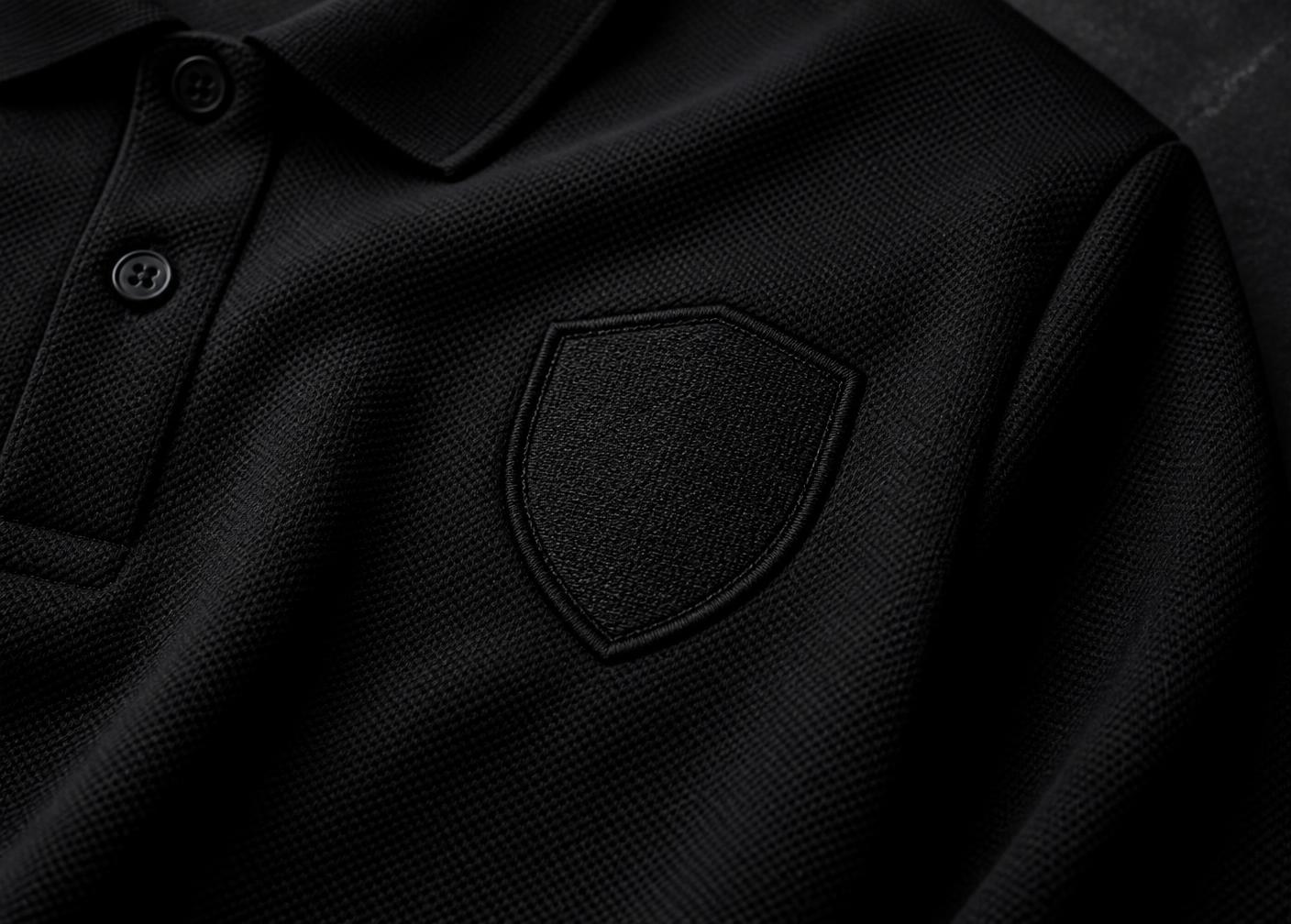 Macro detail of embroidered crest on premium black performance knit
